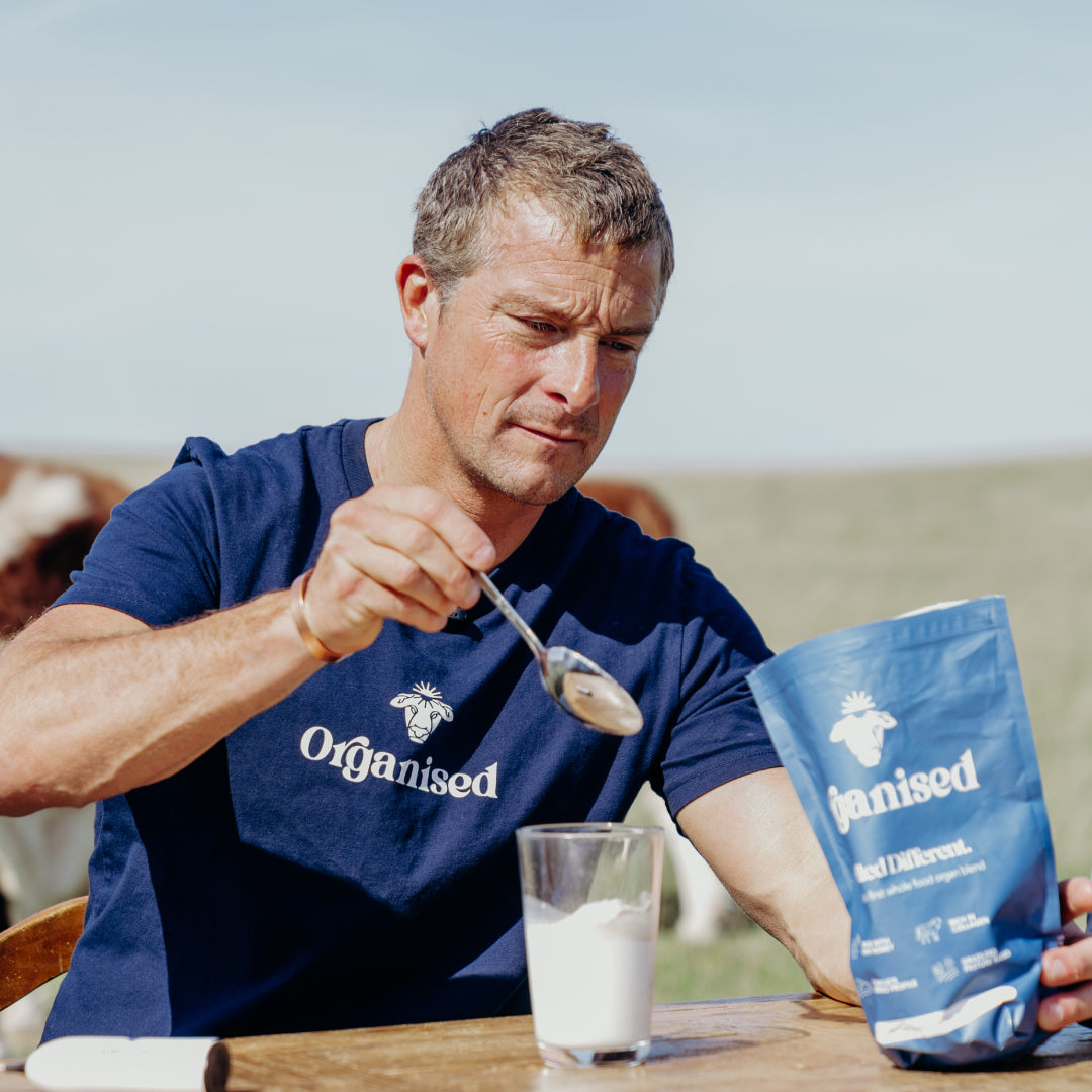 Pot filled with soup, carrots, herbs, and a package labeled 'Organised.'
