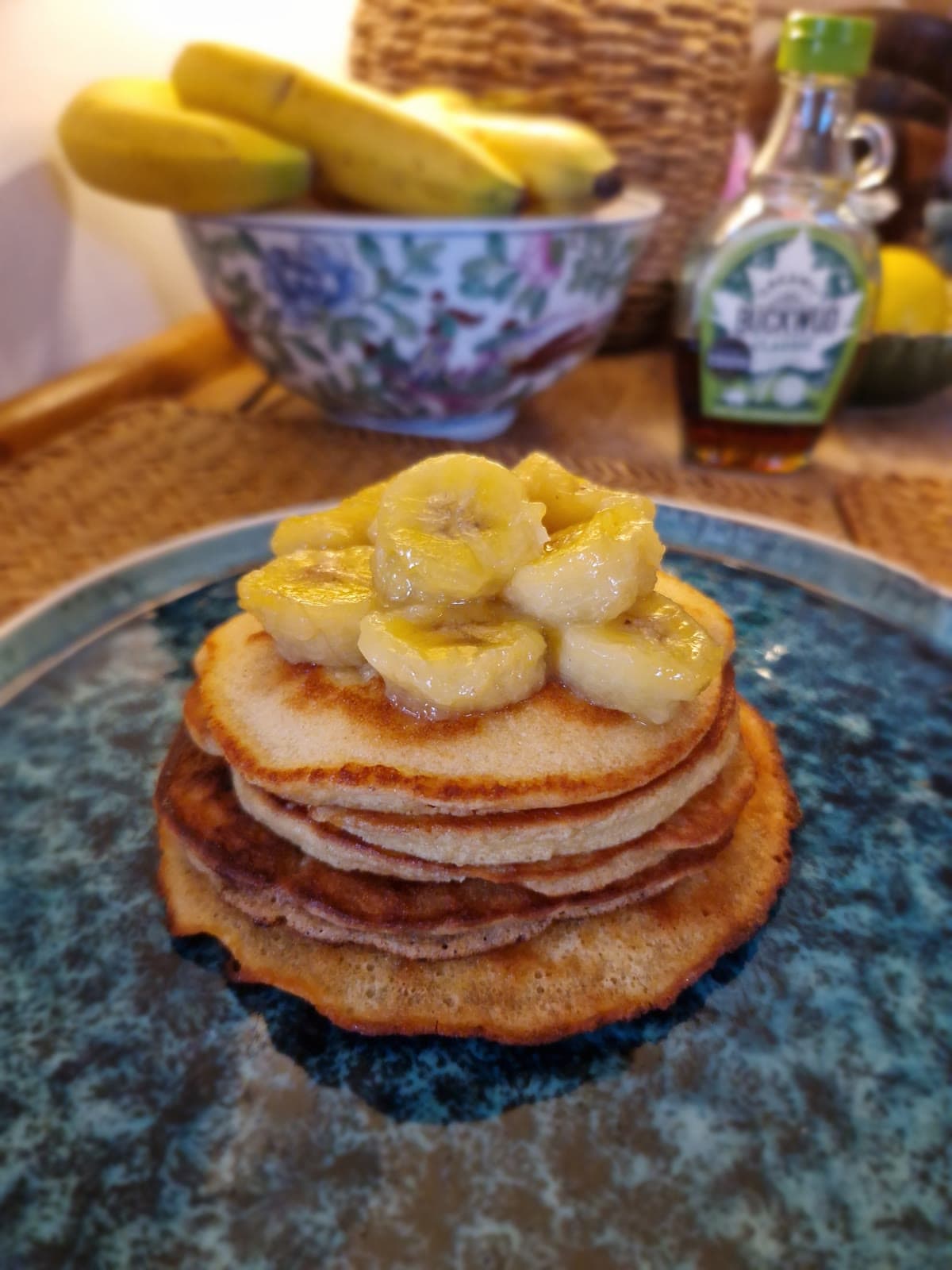 A stack of pancakes topped with caramelised banana slices on a blue plate