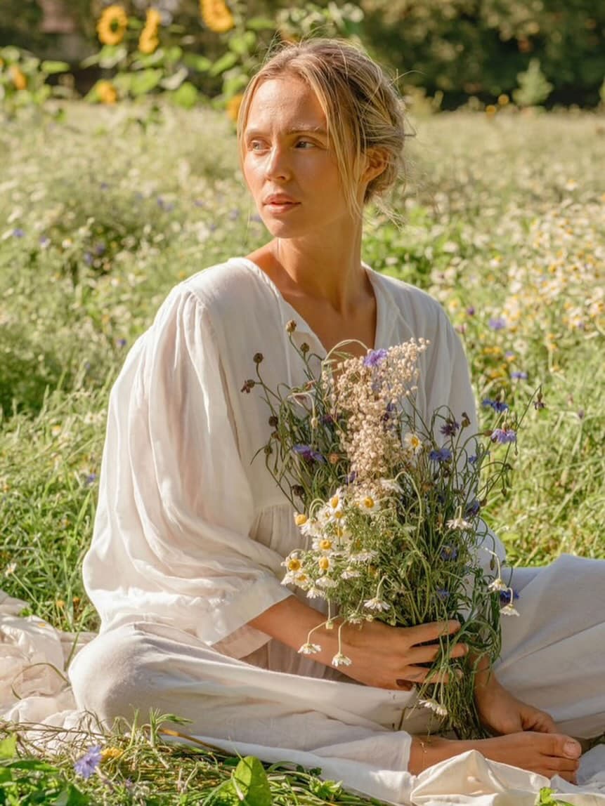 Ruby Thompson sitting in a wildflower meadow, holding a bunch of fresh flowers