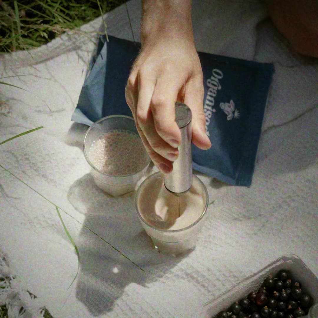 A woman opening the Organised pouch on a kitchen table, a bowl of mince and cut flowers beside her